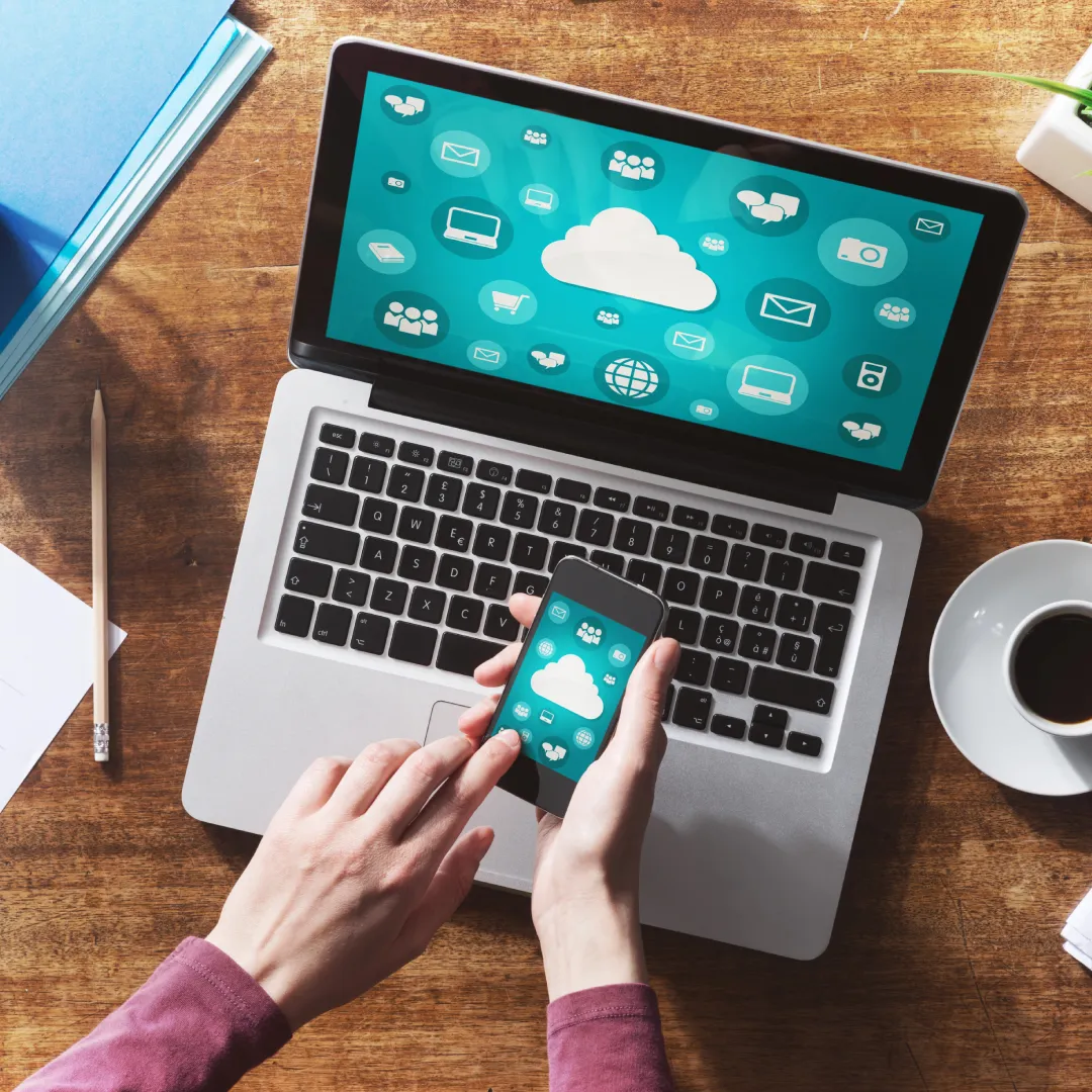 Laptop and smartphone syncing with cloud graphics.