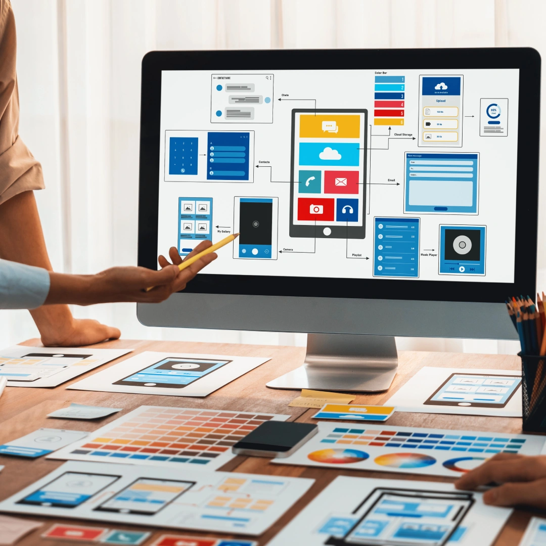Hand pointing at a mobile app architecture diagram on a computer monitor.