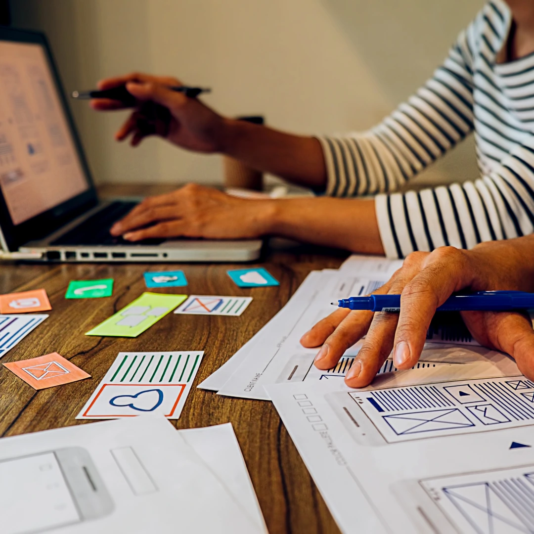 Team designing a digital interface mockup on a wooden desk.