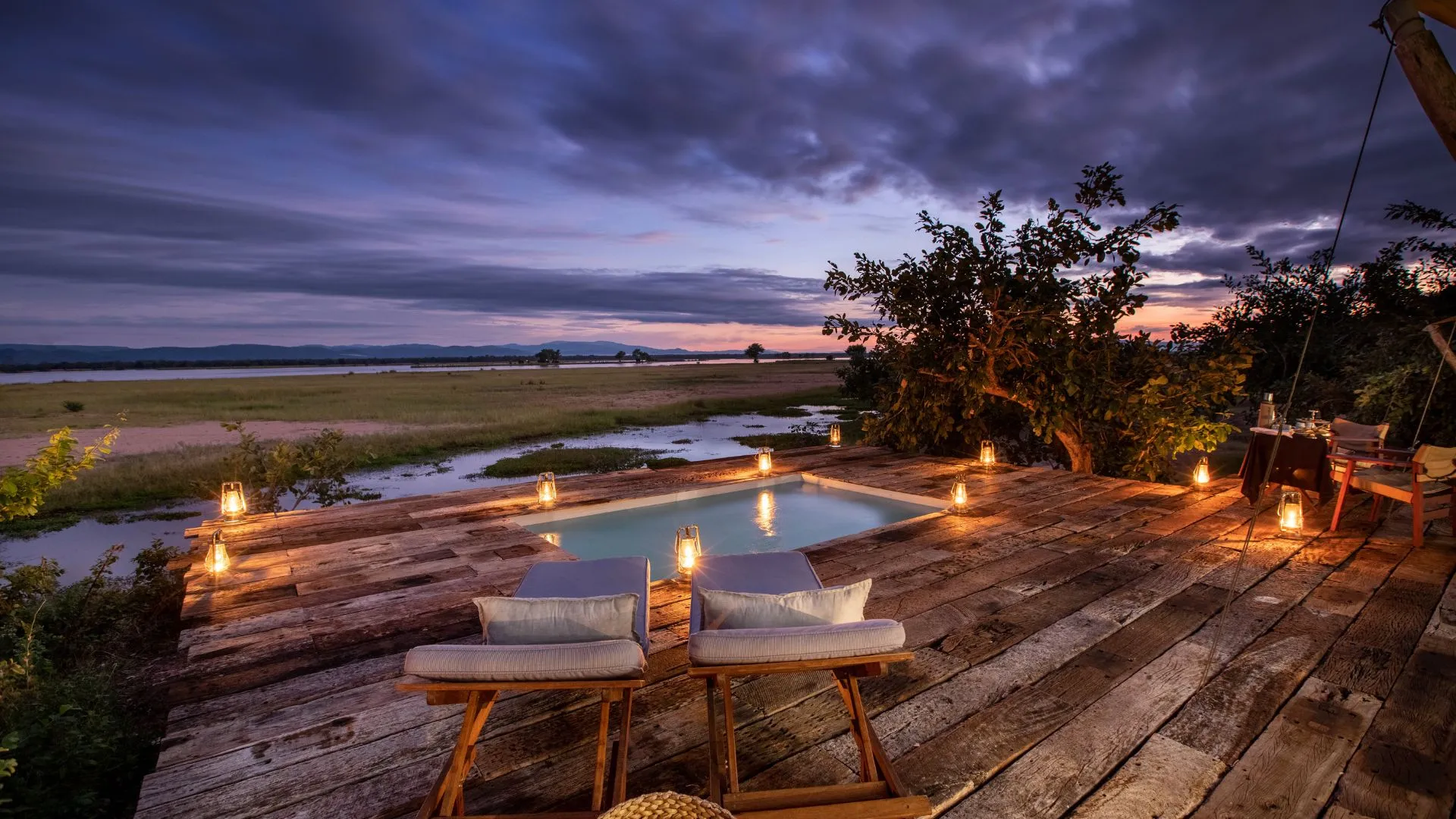 Luxury wooden deck with a small plunge pool and lounge chairs at dusk.
